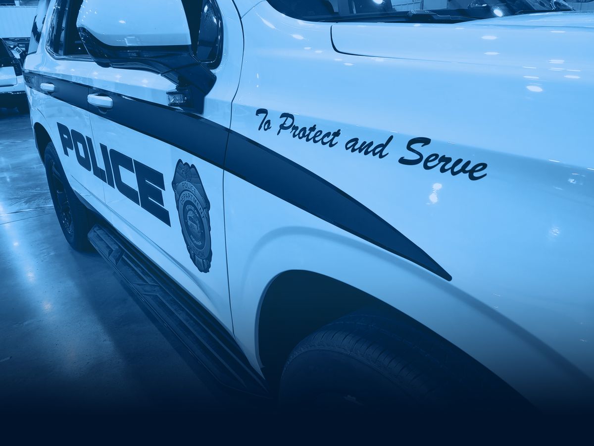 Close-up of police vehicle door graphics reading To Protect and Serve