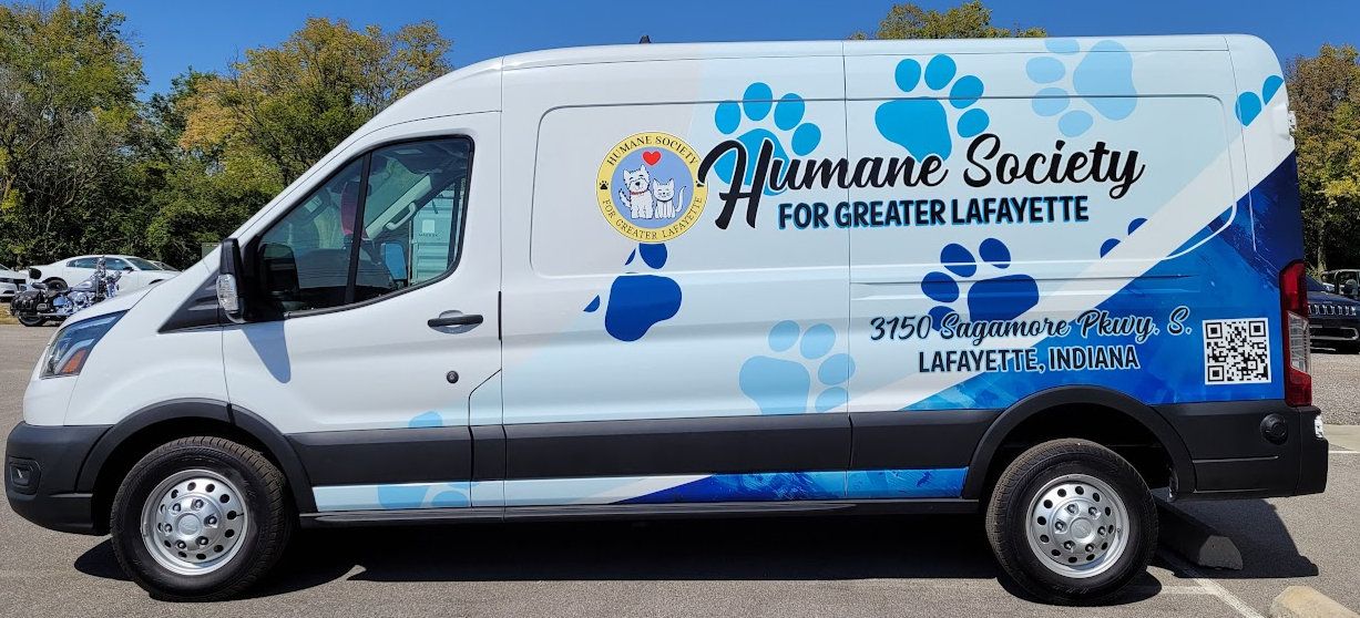 White cargo van with blue paw-print graphics for a local non-profit
